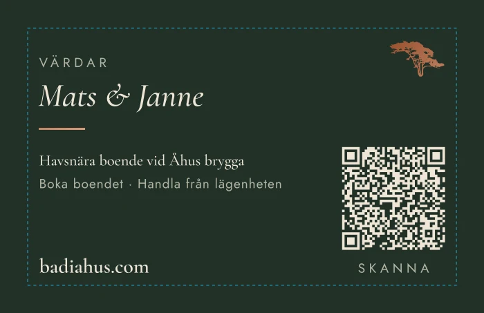 Baksidan på svenska: Värdar, Mats och Janne, Havsnära boende vid Åhus brygga, en QR-kod och badiahus.com.